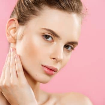 Beauty Concept - Beautiful Woman with Clean Fresh Skin close up on pink studio. Skin care face. Cosmetology.
